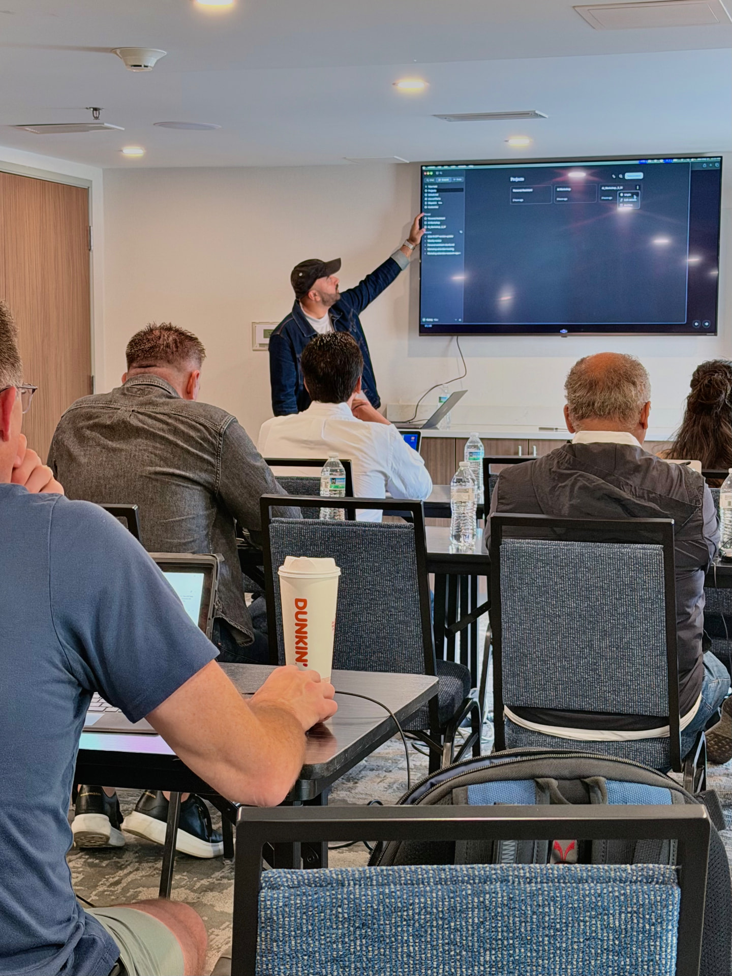 Leading a workshop session, pointing to a screen of AI agent projects